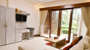 Una sala de estar moderna con un sofá, una mesa de centro, un televisor y una pequeña área de cocina con un microondas.