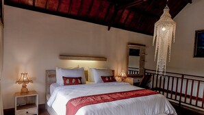 Un dormitorio con cama, mesitas de noche, una lámpara de araña colgante y un cabecero de madera.