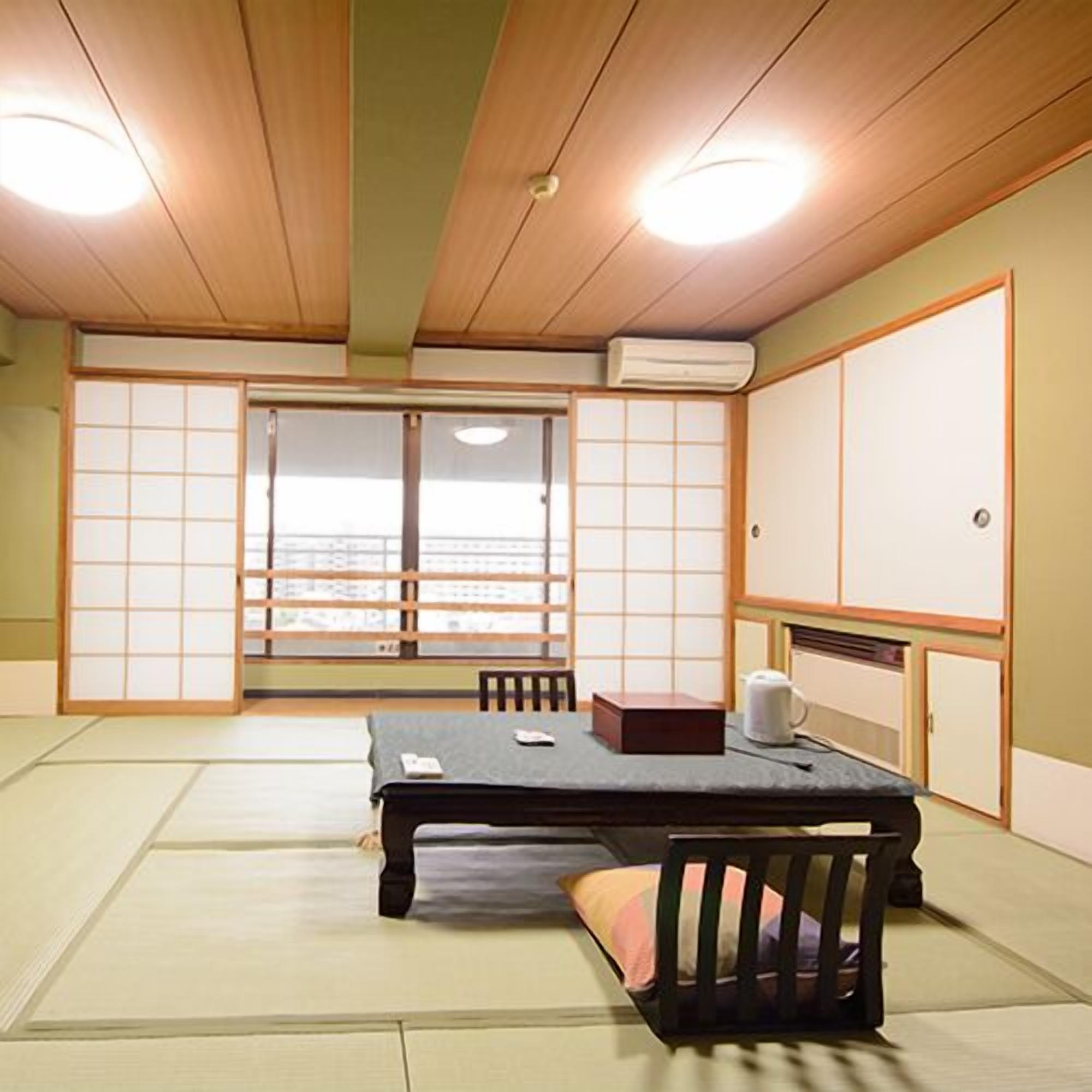 Um quarto japonês tradicional com tatames, uma mesa baixa, um assento e portas deslizantes.