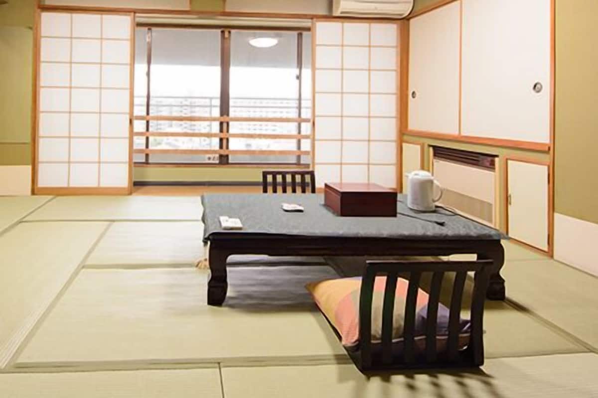 A traditional Japanese room with tatami flooring, a low table, a cushion, and sliding doors.