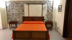 A bedroom with a wooden bed, stone wall, and a small bedside table. - Eleven Bed & Breakfast (Reggio Calabria)