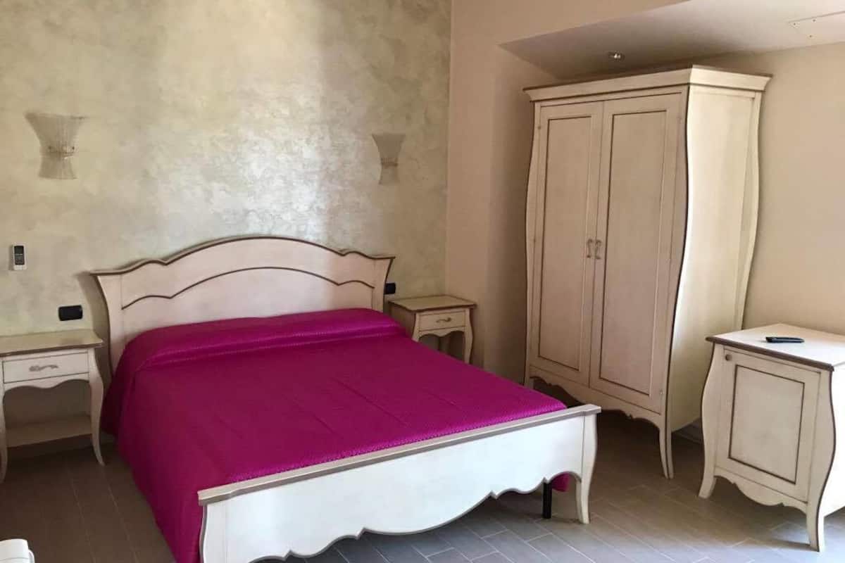 A bedroom with a bed, a wardrobe, a bedside table, and a nightstand.