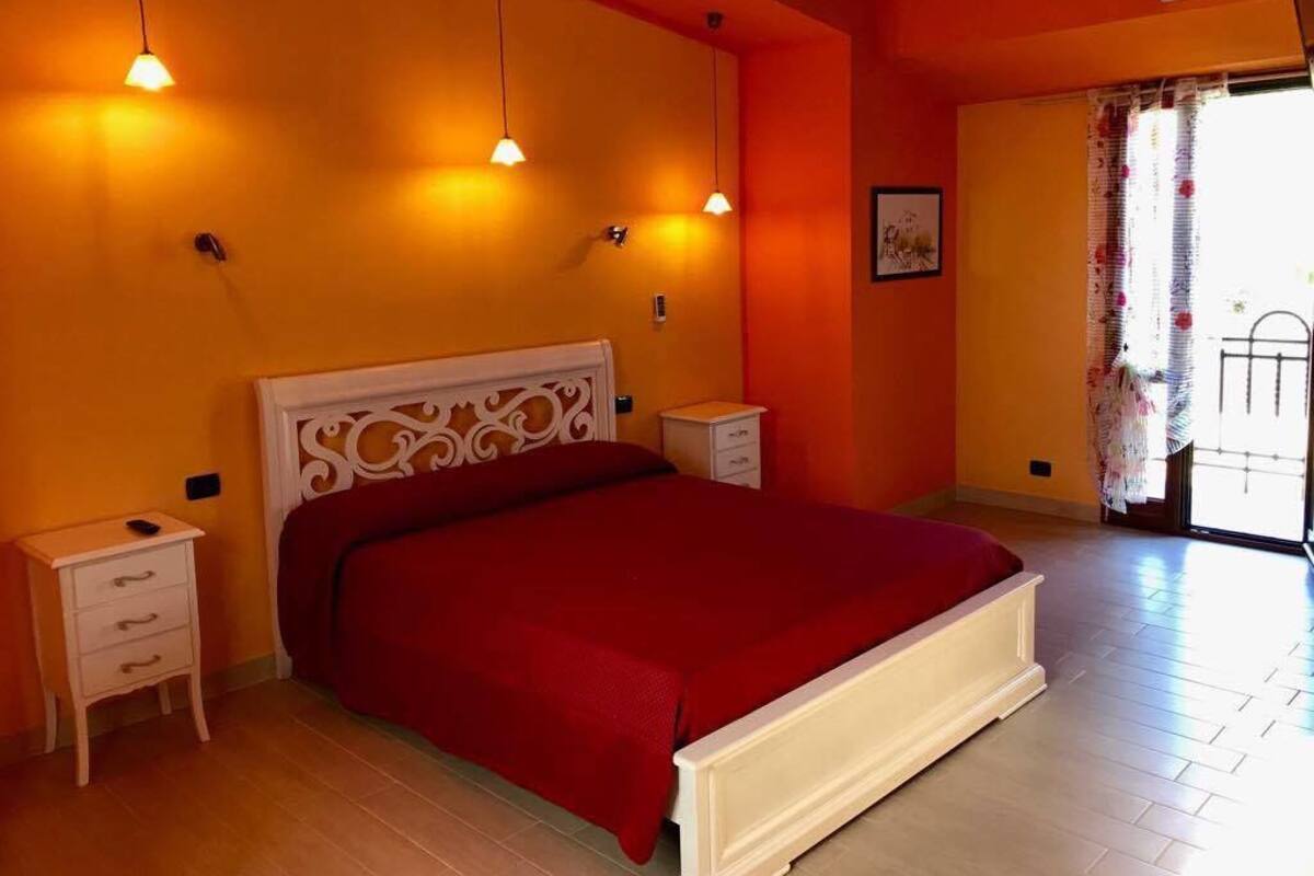 A bedroom with a large bed, two bedside tables, and a window with curtains.