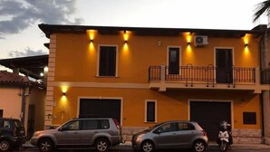 A two-story building with a yellow facade, two cars parked in front, and a balcony with a railing. - Eleven Bed & Breakfast (Reggio Calabria)