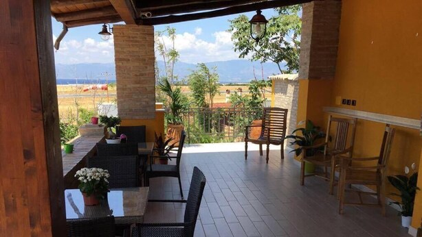 A covered patio with wicker furniture, potted plants, and a view of the countryside. - Eleven Bed & Breakfast (Reggio Calabria)