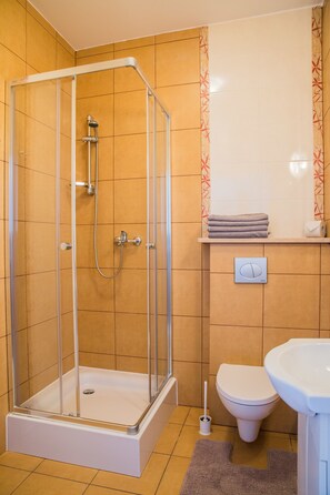 Une salle de bain avec une douche à parois de verre, des toilettes et un lavabo.