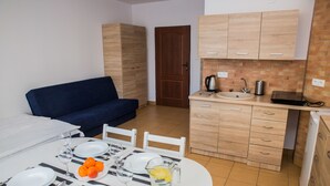 A compact kitchen with a sink, cabinets, and a dining area with a table set for two. - Family Homes - Apartamenty Vento (Wladyslawowo)