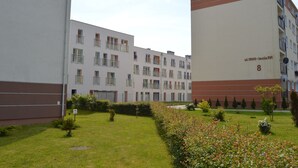 A multi-story residential building with balconies, a well-maintained lawn, and a clear sky. - Family Homes - Apartamenty Vento (Wladyslawowo)