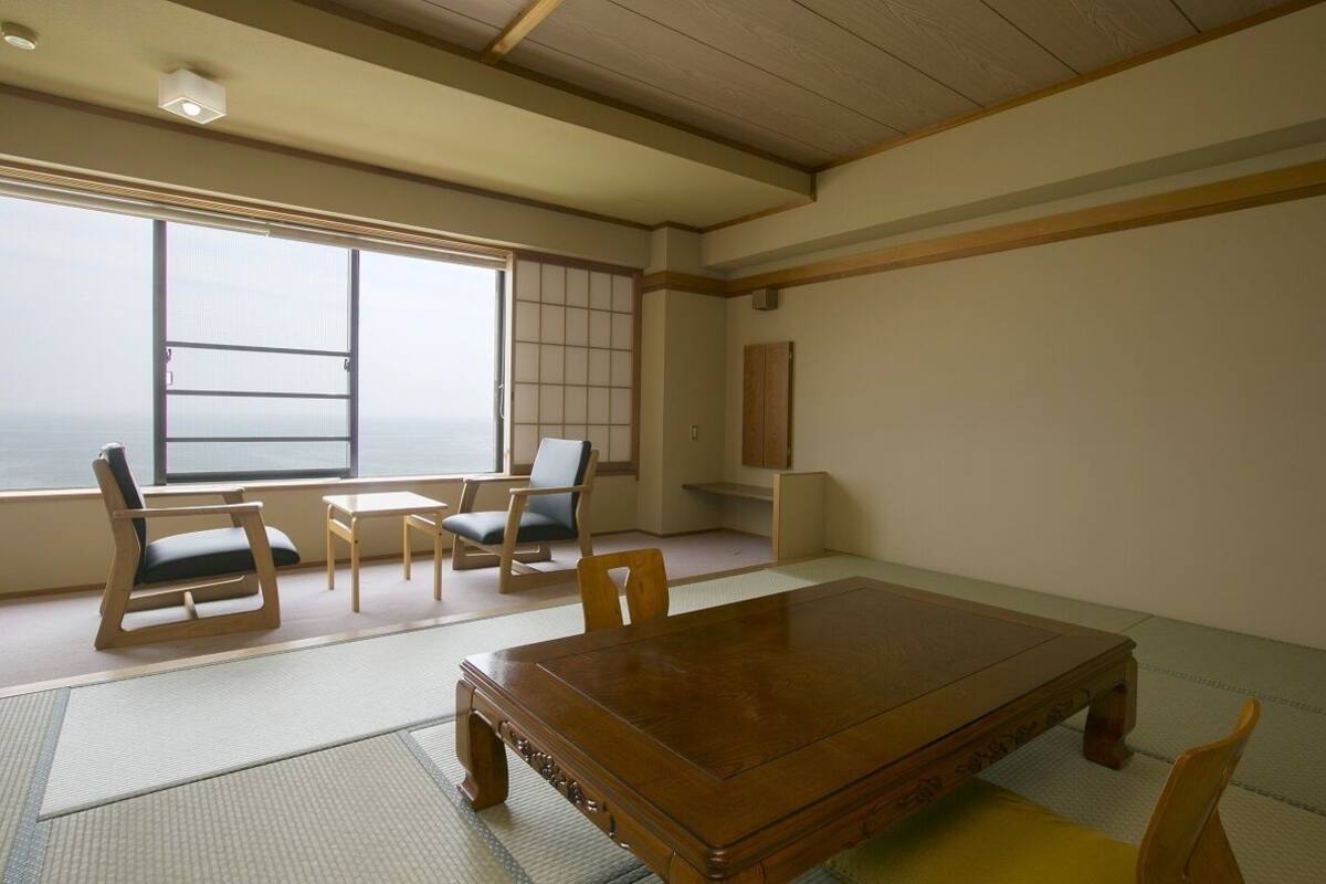 A traditional Japanese room with tatami flooring, a wooden table, and low wooden chairs.