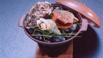 A ceramic pot with various seafood items on a wooden board.