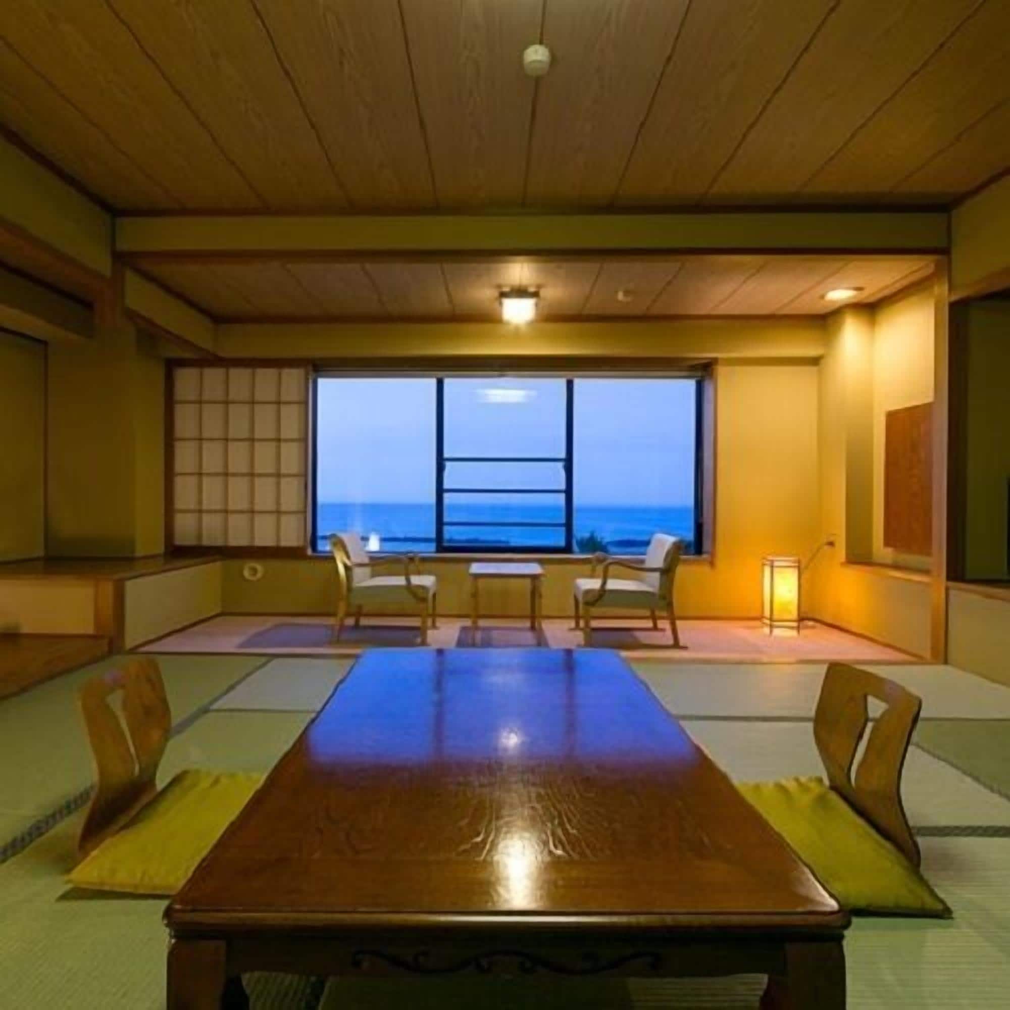 A traditional Japanese room with tatami flooring, a wooden table, and chairs.