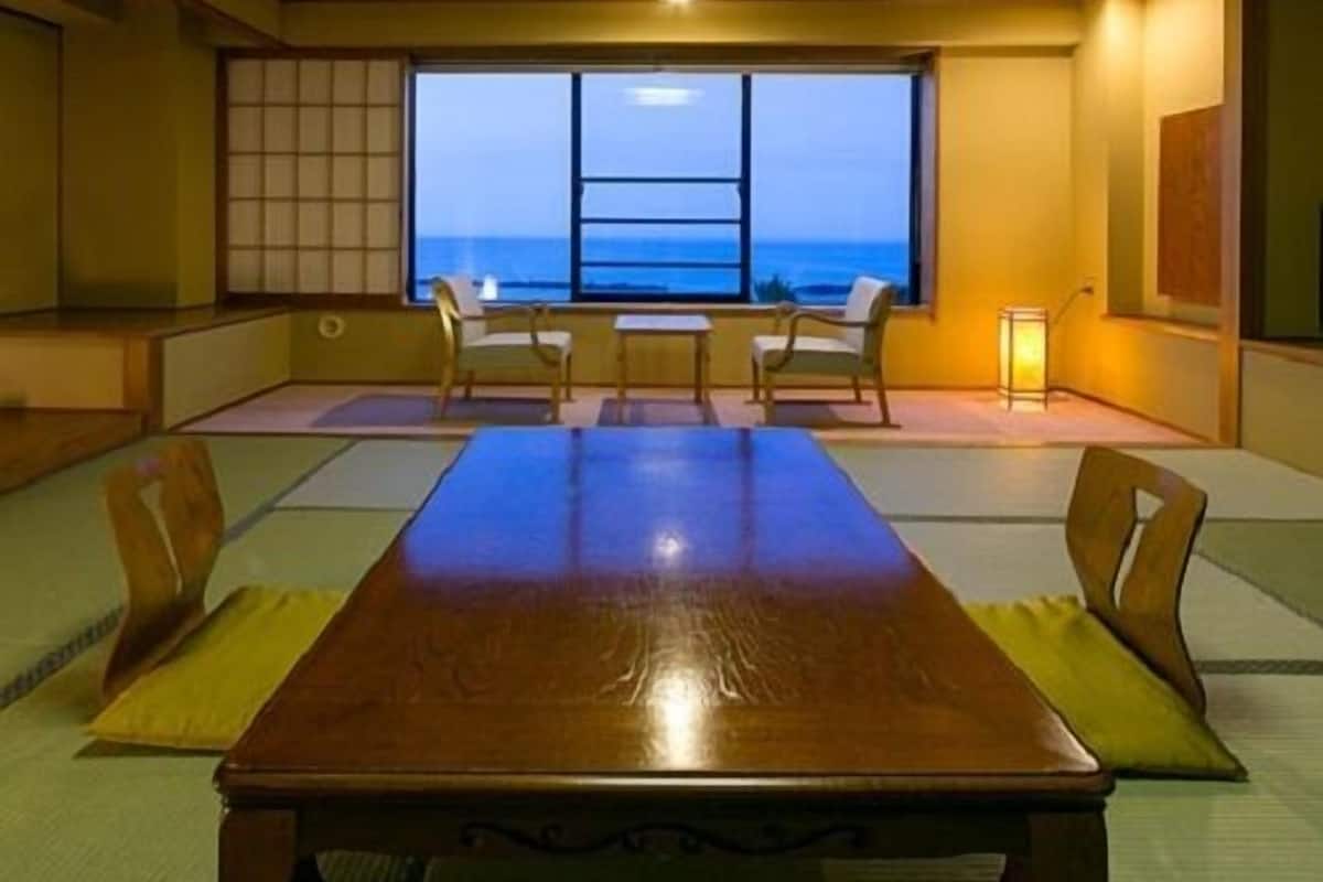 A traditional Japanese room with tatami flooring, a wooden table, and chairs.
