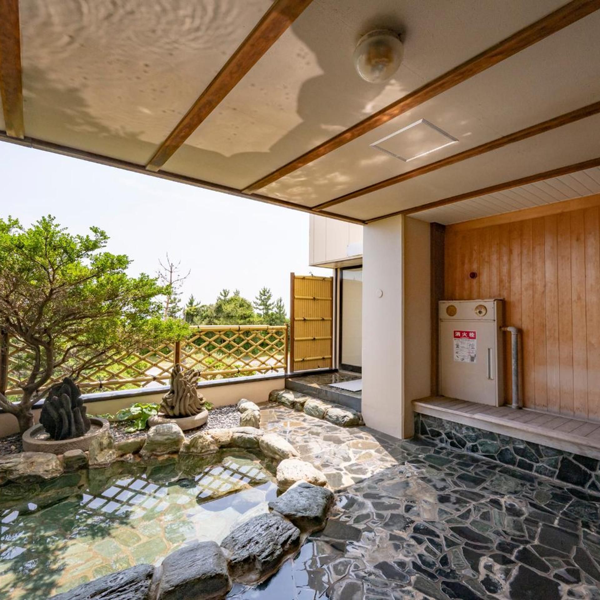 A traditional Japanese-style room with tatami flooring, a stone water feature, and a wooden door.