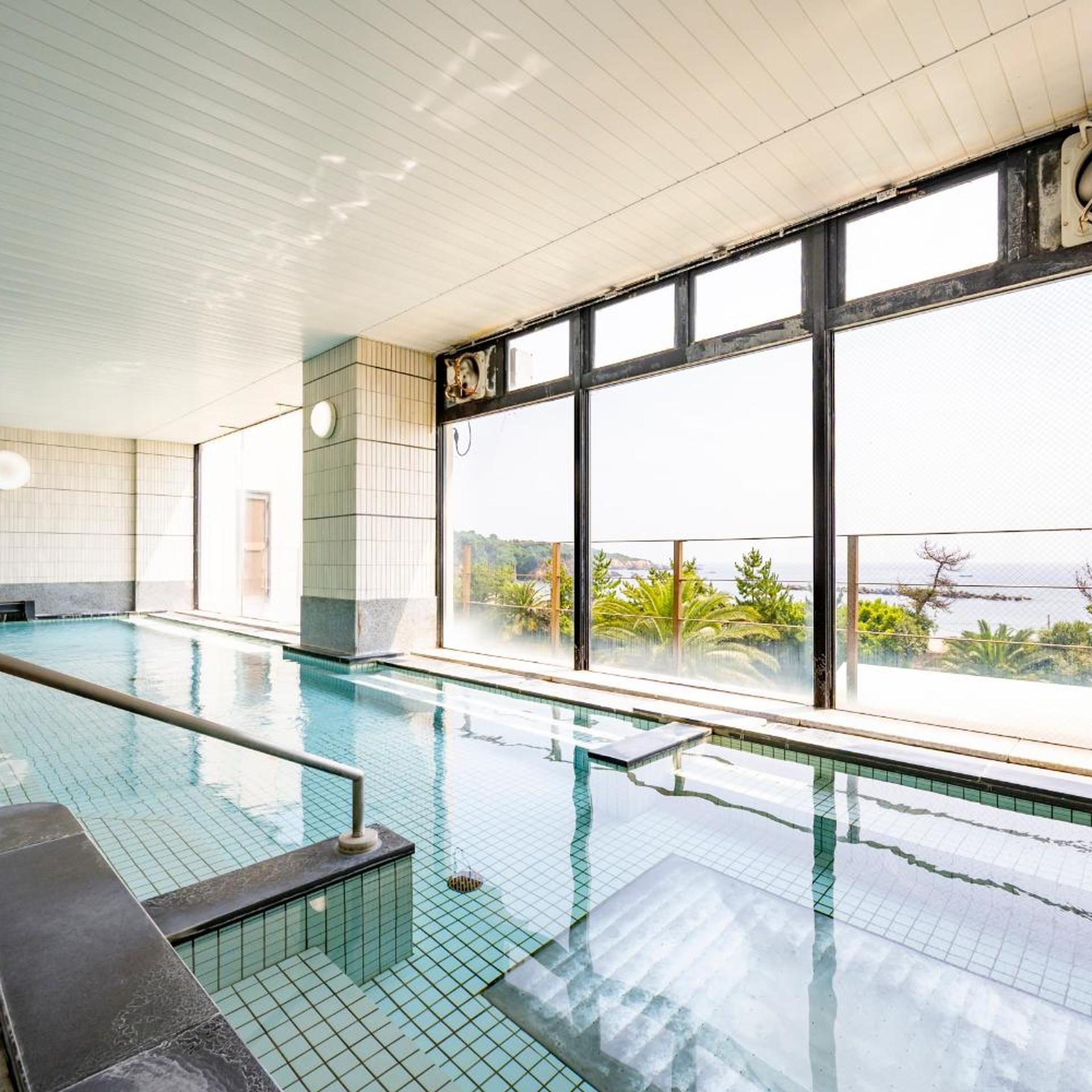 Ein Innenpool mit Glaswänden und Meerblick.