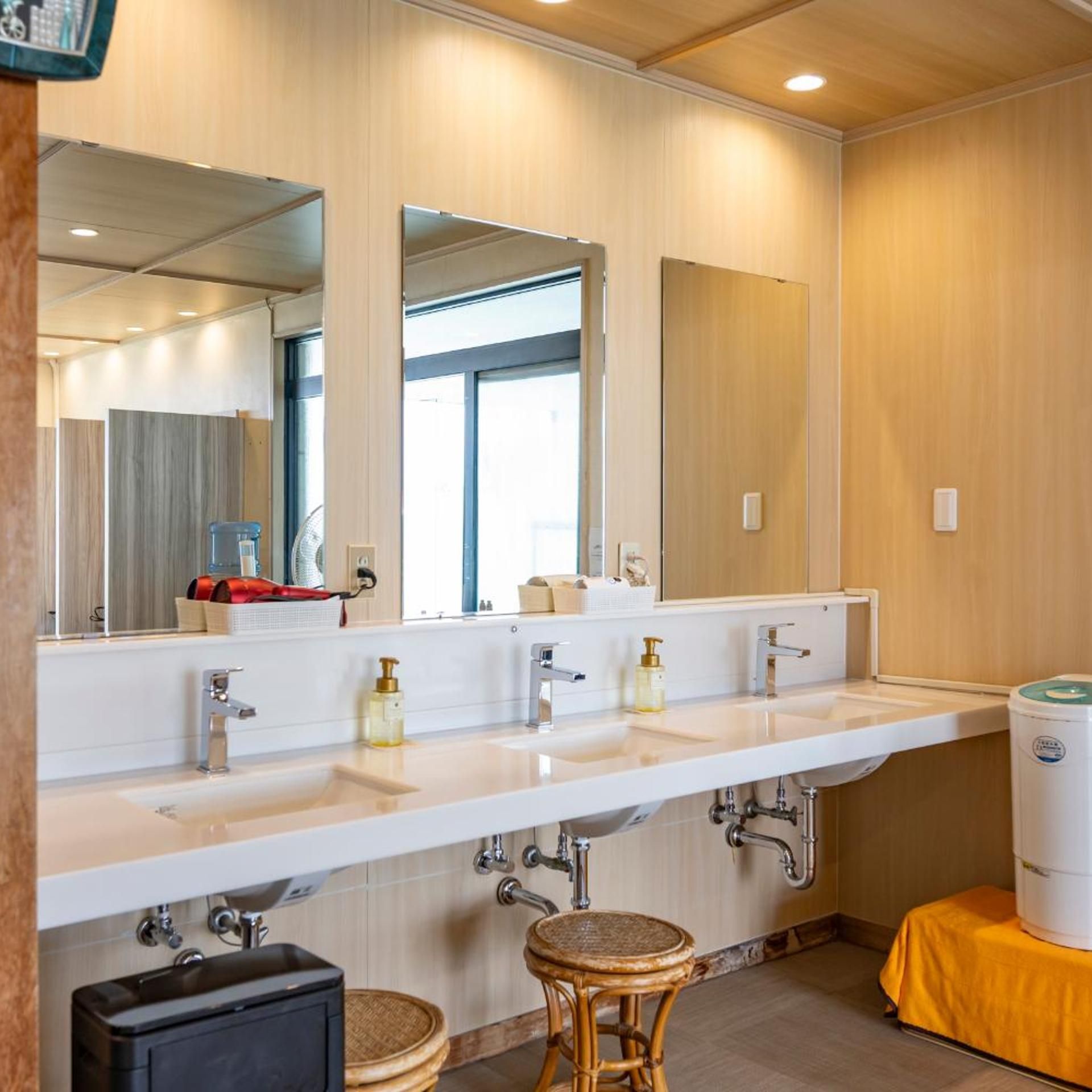 Ein modernes Badezimmer mit einem großen Spiegel, zwei Waschbecken und einer Toilette.