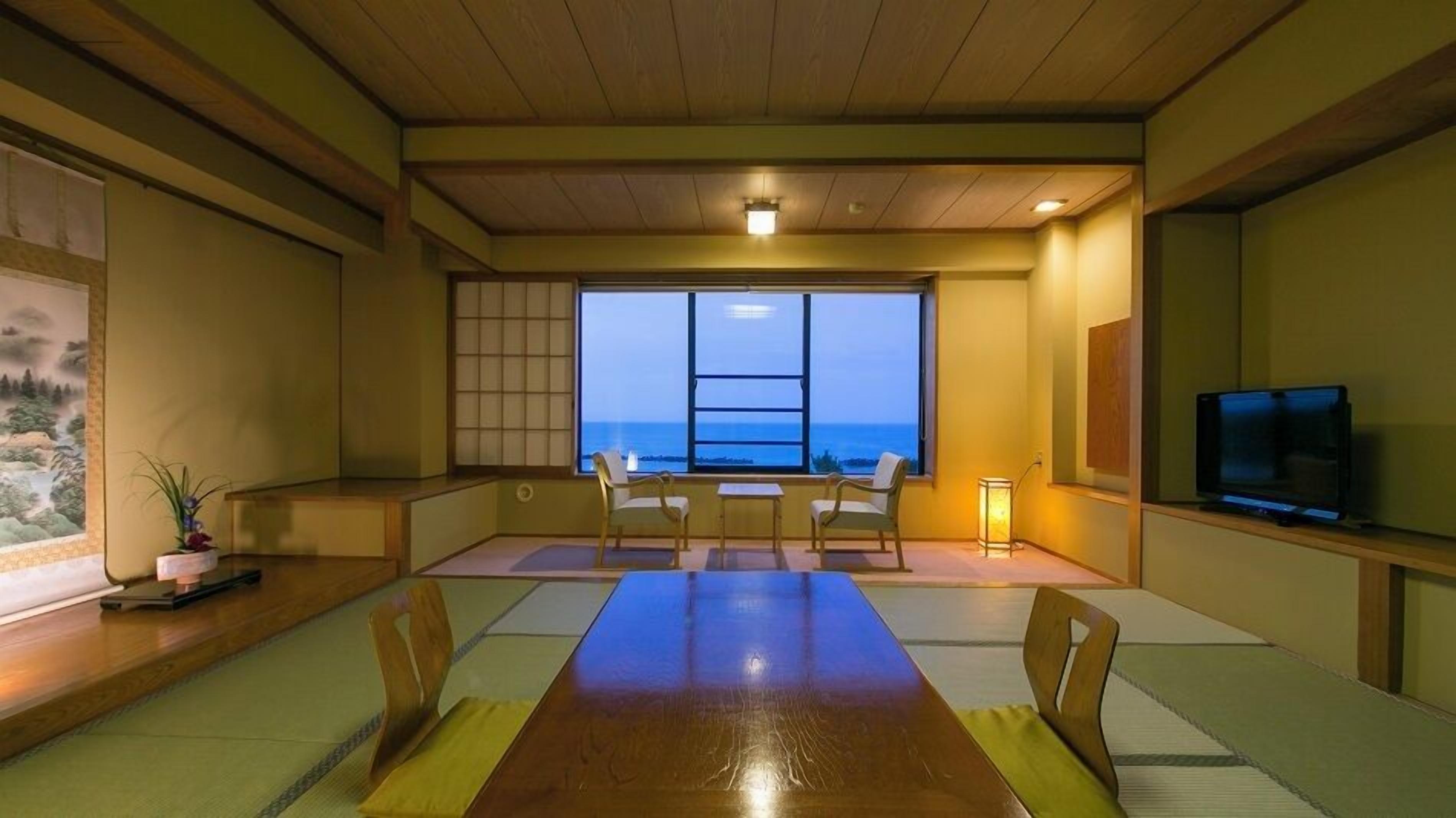 A traditional Japanese-style room with tatami flooring, a low table, and a television.