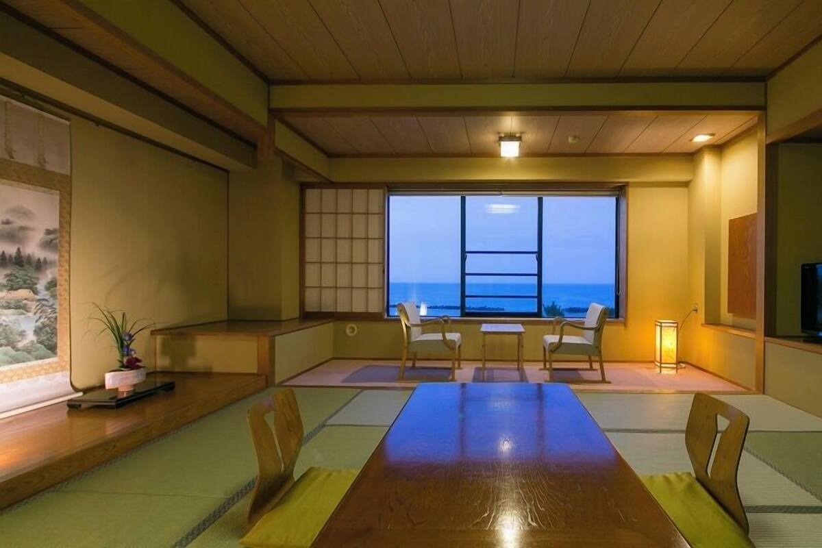 A traditional Japanese-style room with tatami flooring, a low table, and a television.