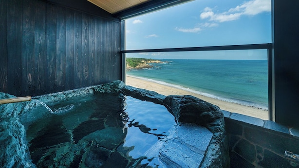 Tinaja de piedra con interior de madera y vista a una playa y al océano.