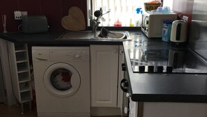 Eine kleine Küche mit Waschmaschine, Toaster und Mikrowelle.