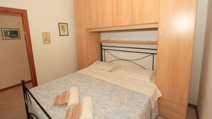 Une chambre à coucher avec un lit, une armoire en bois et deux tableaux encadrés accrochés au mur.