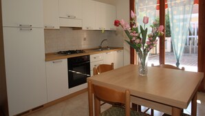 Une cuisine moderne avec des meubles blancs, un plan de travail en bois et un coin repas comprenant une table et des chaises.