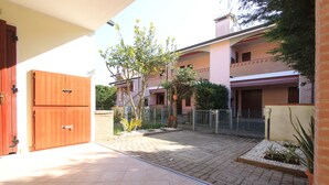 Une cour avec un sol carrelé, une porte en bois et un bâtiment doté d’un balcon.