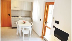 A modern kitchen with white cabinetry, a dining table with chairs, a stove, and a sink. - Residence Rendez Vous (Vieste)