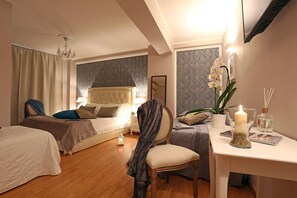 A hotel room with two beds, a chair, a table with a candle, and a mirror. - Liberty Vatican Suites (Rome)