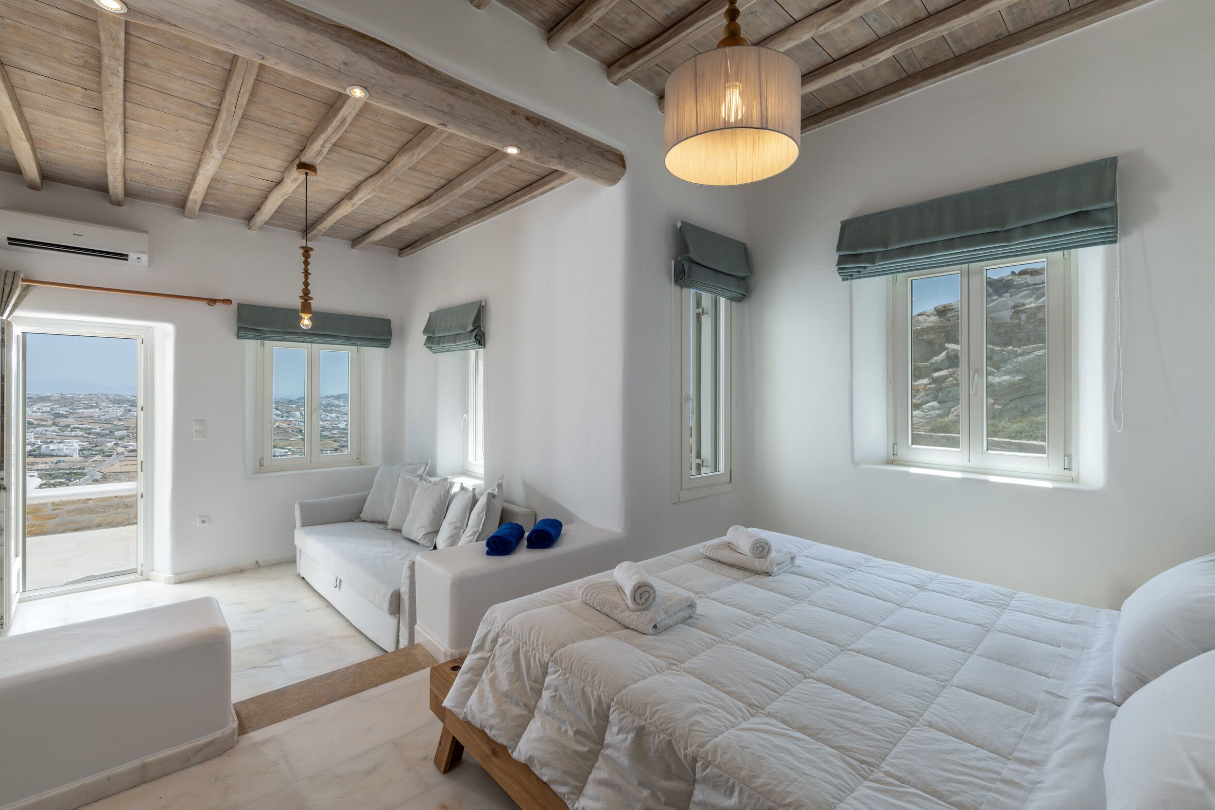 Un dormitorio con una cama grande, un sofá y vistas de la ciudad.