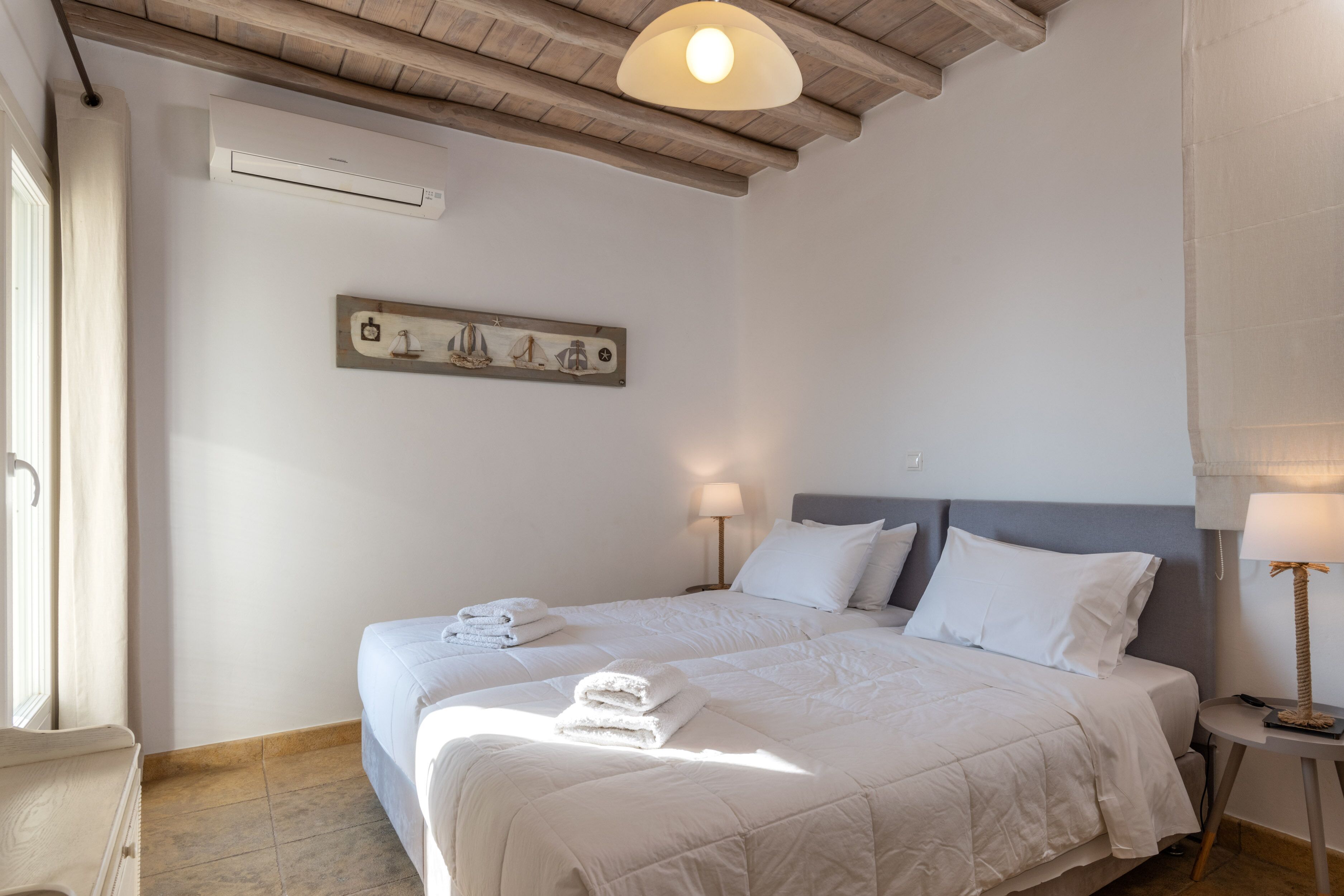 Habitación de hotel con una cama grande, dos mesitas de noche, un aire acondicionado de pared y un adorno sobre la cama.