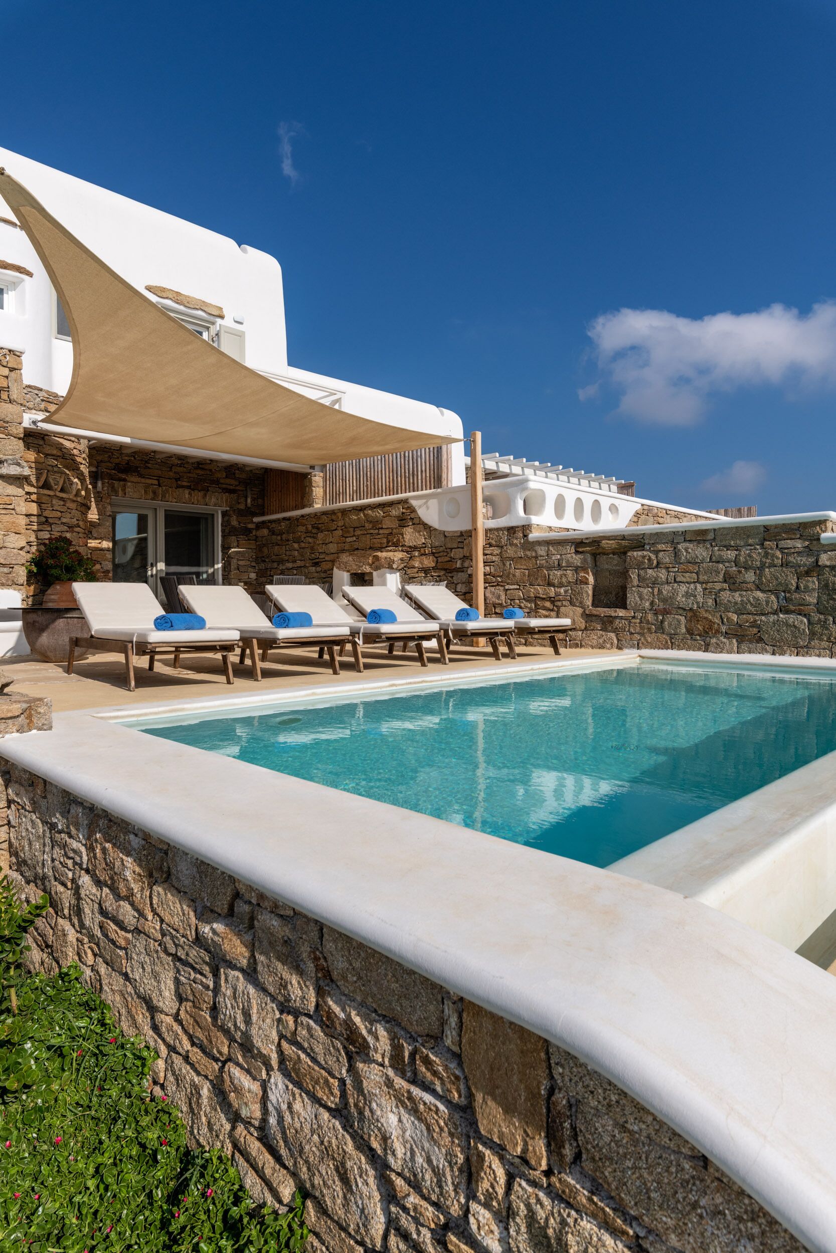 A poolside area with lounge chairs and a stone wall.