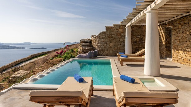 A pool area with lounge chairs and a pergola overlooking a scenic view. - Mykonos Divino (Mykonos)