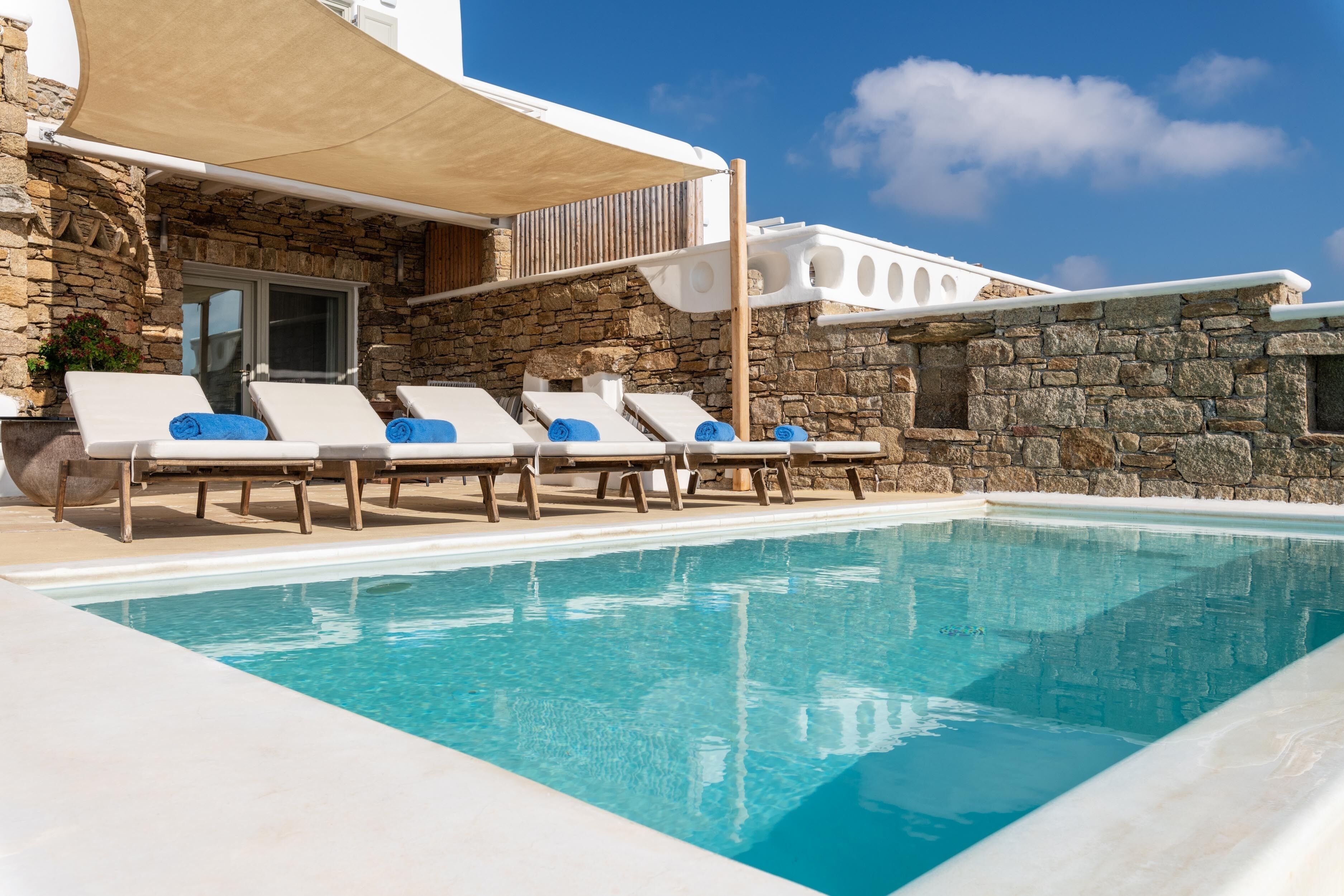 A poolside area with lounge chairs and a stone building.