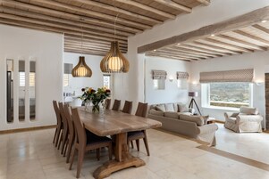 Un'ampia zona giorno con un tavolo da pranzo in legno, diverse sedie, un divano e una finestra con vista.