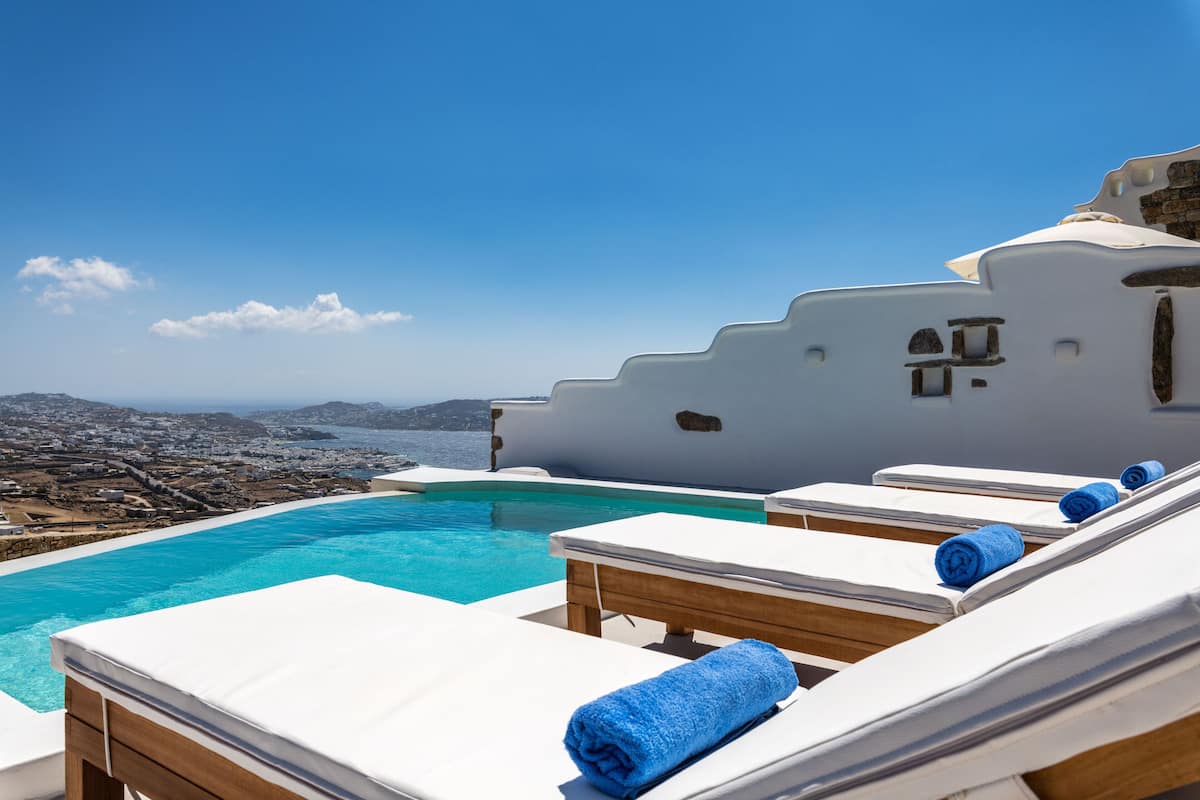 A poolside area with lounge chairs and a view of the city and sea.