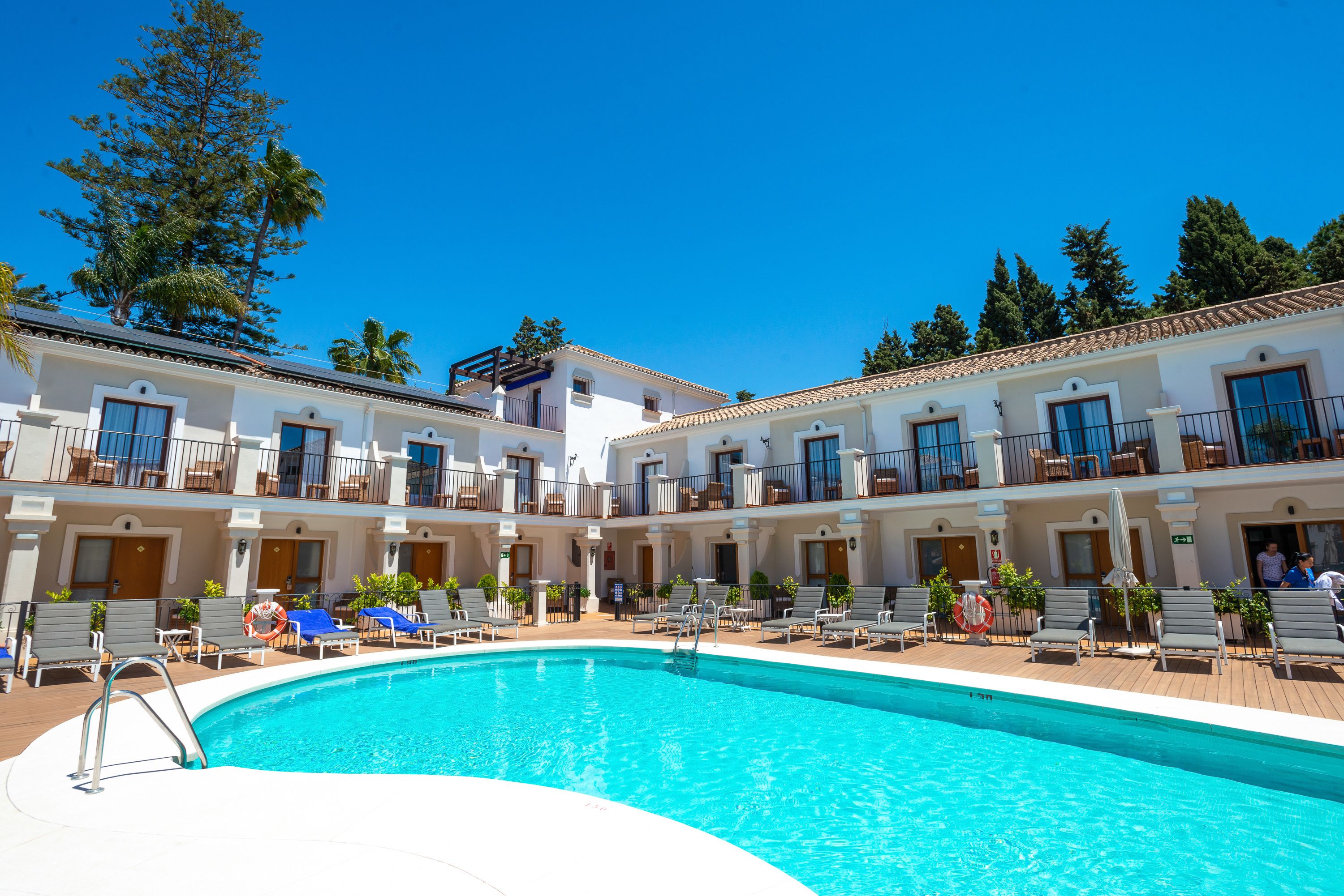 Un hotel con piscina, varios balcones y un cielo azul despejado.