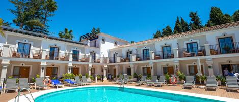 Un hotel con piscina, varios balcones y un cielo azul despejado.