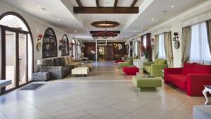 Un vestíbulo amplio con techo alto, ventanas grandes y diversas opciones de asientos, incluyendo sofás y sillones.