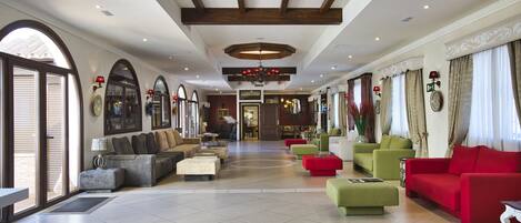 A spacious lobby with a high ceiling, large windows, and a variety of seating options including sofas and armchairs.