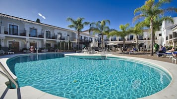 Una piscina al aire libre, sombrillas, tumbonas