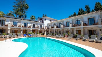 Un hôtel doté d’une piscine, de nombreux balcons et offrant une vue sur un ciel d’un bleu éclatant.