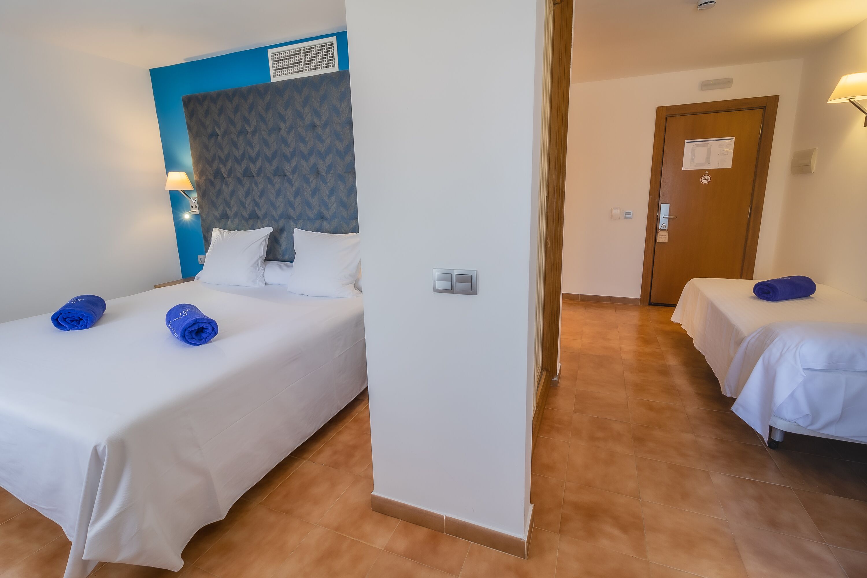Une chambre d’hôtel avec deux lits, chacun étant équipé de draps blancs et de serviettes bleues.