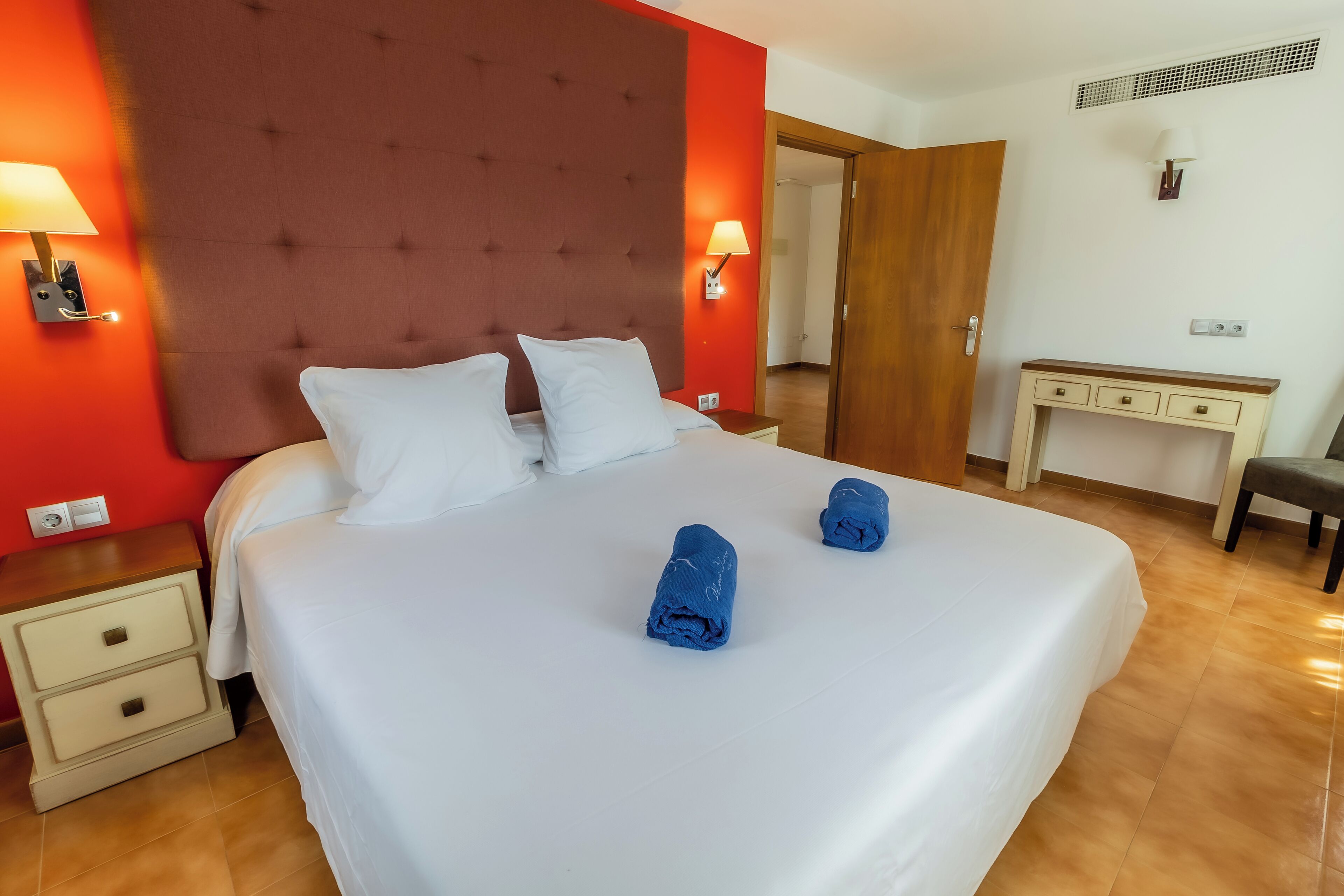 A hotel room with a large bed, two bedside tables, a desk, and a chair.