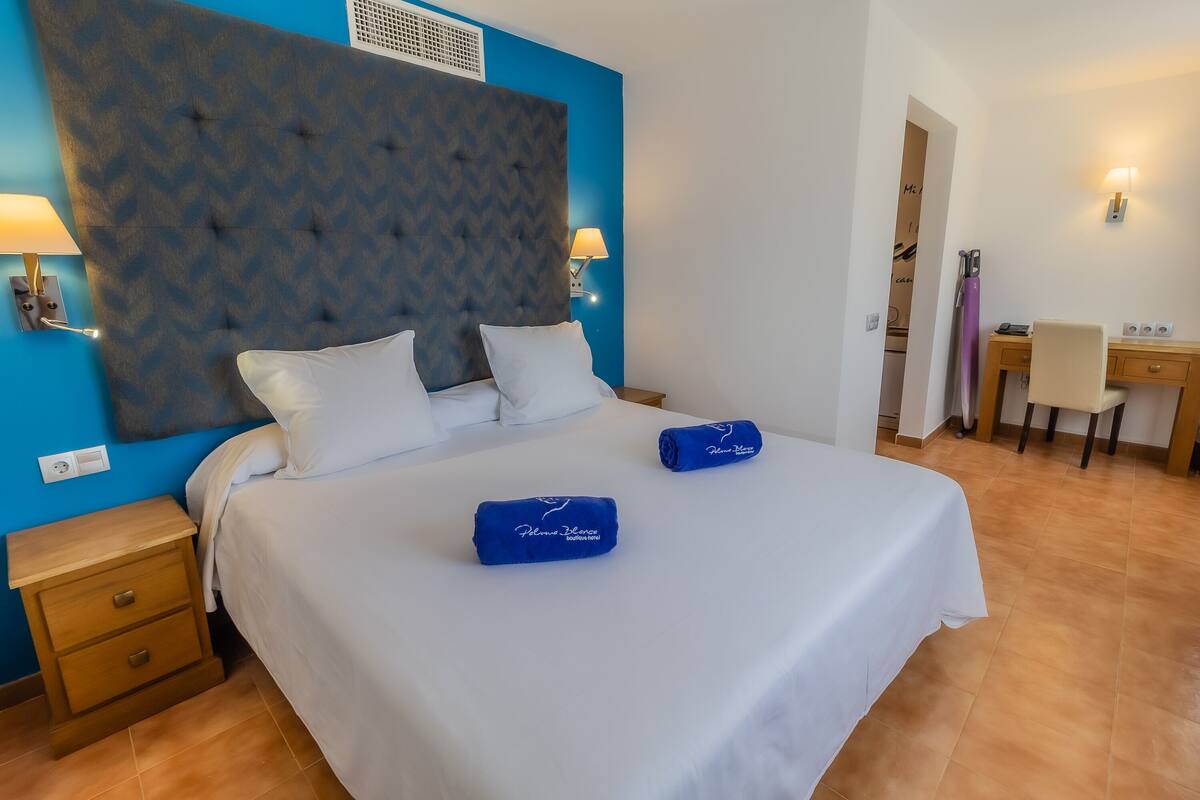 A hotel room with a large bed, two bedside tables, a desk, and a chair.