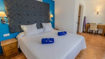 Una habitación de hotel con una cama grande, dos mesitas de noche, un escritorio y una silla.