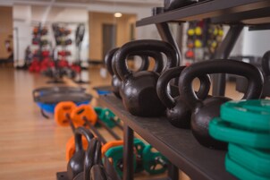 Een sportschool met kettlebells en gewichten op rekken.