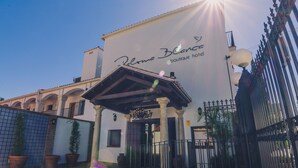 Entrada de un hotel boutique con un letrero que dice "Paloma Blanca boutique hotel", un acceso cubierto y una valla de hierro decorativa.
