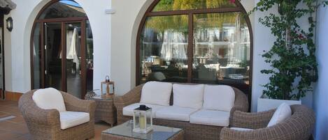 A patio with wicker furniture, including a sofa and two armchairs, a small table, and a glass coffee table.