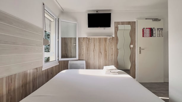 A modern hotel room with a large bed, a TV mounted on the wall, and a shower area. - Fasthotel La Roche sur Yon Un FH CONFORT (La Roche-sur-Yon)
