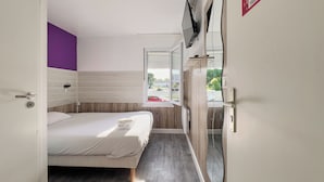 A modern bedroom with a bed, a window, and a wardrobe. - Fasthotel La Roche sur Yon Un FH CONFORT (La Roche-sur-Yon)